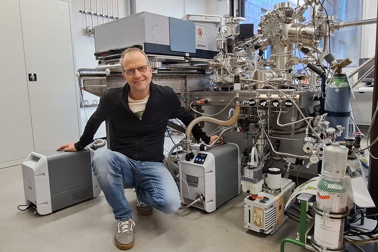 Dr. Volkmar Zielasek standing in front of the Fourier-transform infrared spectrometer and UHV system – with two VACUU·PURE® vacuum screw pumps