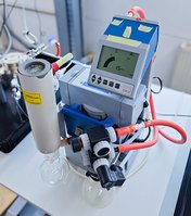 Table with chemically resistant MD 4C vacuum diaphragm pump with glass waste vapor condenser – in use for manometric permeation testing.